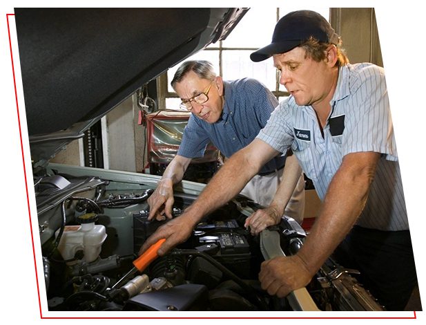 Two men working on a car in an auto shop.